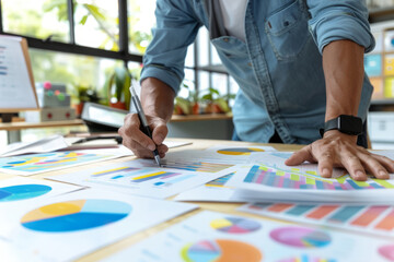 Businessman reviewing and analyzing financial charts and graphs at a desk in a bright office