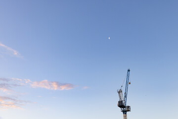 Construction crane isolated in blue sky with moon