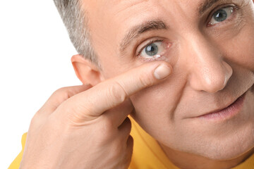Mature man putting in contact lenses on white background, closeup