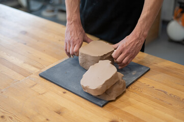A potter cuts a piece of clay into pieces before using it in the workshop. 