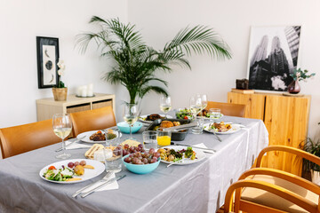 Bright dining table with food and drink ready for lunch, no people.