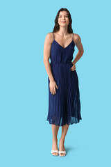 Beautiful young woman in stylish dark dress on blue background