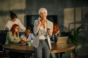 Senior businesswoman having phone call on a meeting of interracial team