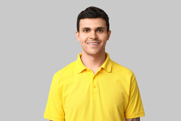 Handsome young man in stylish yellow t-shirt on grey background, closeup