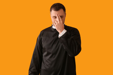 Young priest cross oneself on yellow background