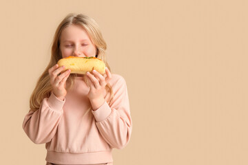 Cute little girl eating tasty hot dog on color background