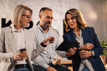 Mature businessman with tablet collaborating with colleagues on project