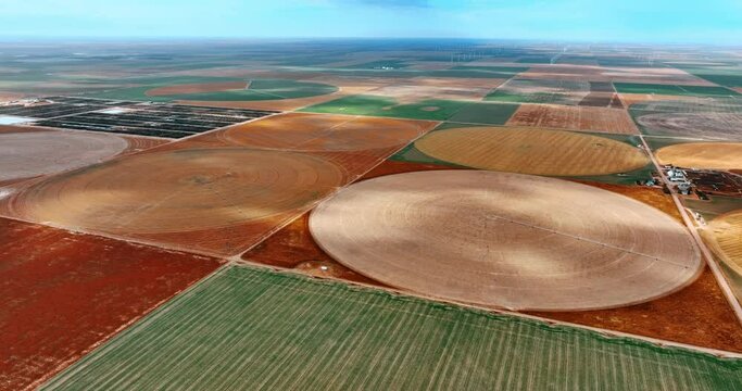 Squares and circles of diverse colors on the vast field. Aerial perspective on the circular farms with yet no crops planted or appeared.