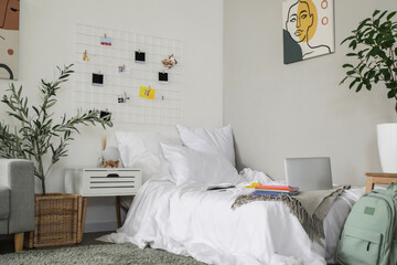 Laptop with copybooks on bed in student's room