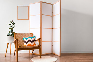 Interior of living room with wooden folding screen, armchair and blank frame