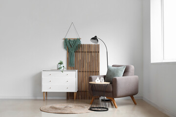 Interior of light living room with wooden folding screen, armchair and commode