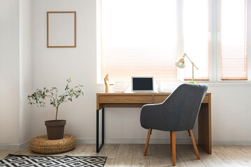 Interior of light room with workplace and blank frame