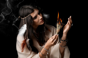 Beautiful female shaman with herbs on dark background