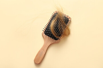Brush with hair strand on beige background. Hair loss problem