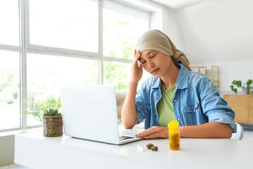 Young Asian woman after chemotherapy with laptop and weed sitting at home