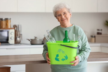Senior woman with garbage bin in kitchen. Waste sorting concept