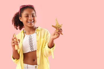 Little African-American girl with sunscreen cream and starfish on pink background