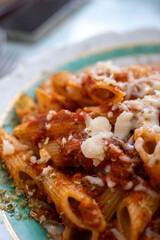 penne pasta with cheese and tomatoes on vintage plate in close-up
