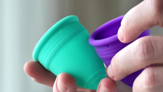 Womens periods.reusable silicone menstrual cup.Silicone mestrual cups in hands close-up. Zero vaste and reasonable hygiene and consumption. Womens health and hygiene items. 4k footage