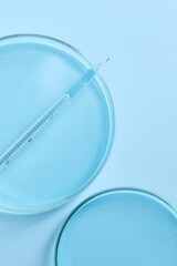 Transfer pipette and petri dishes on light blue background, flat lay