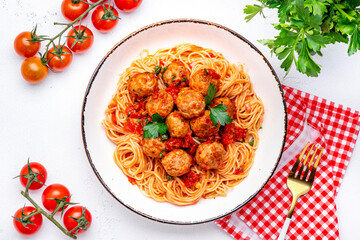 Spaghetti with meatballs in marinara sauce, top view, white table