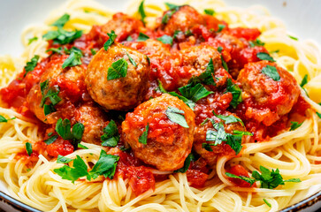 Spaghetti with meatballs in marinara sauce, top view, white table