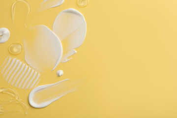 Samples of face cream on yellow background, top view. Space for text