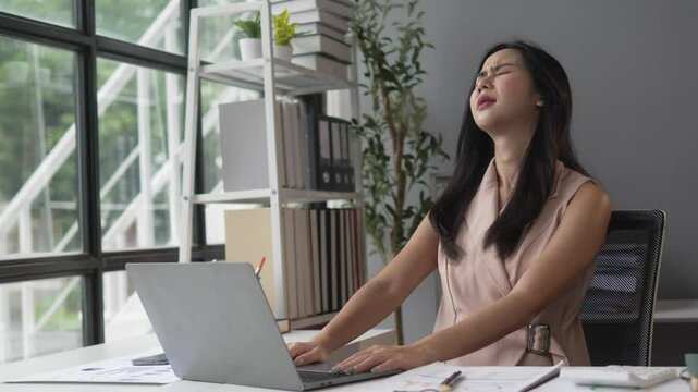 Stressed businesswoman working on laptop in modern office. Captures her emotional struggle in slow motion. Shows frustration and stress in workplace