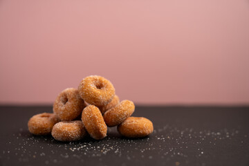 ピンク背景の山盛りになった小さなドーナツ