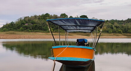 Small traditional boat on calm waters, dense vegetation in the background