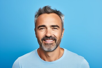Obraz premium Portrait of handsome middle-aged man with beard and mustache on blue background
