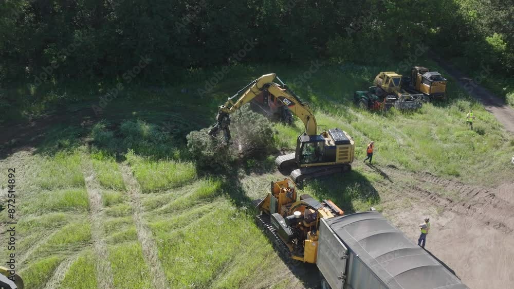 Poster view of automated machines transforming cut trees into minute particles in a forest. aerial shot.