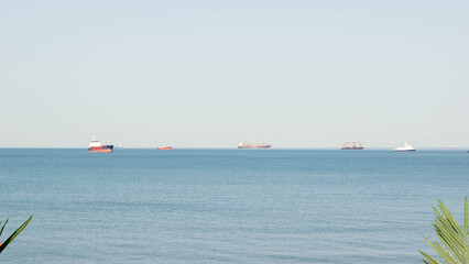 Fototapeta premium Cargo Ships and Boats on Calm Blue Sea Horizon on a Clear Day