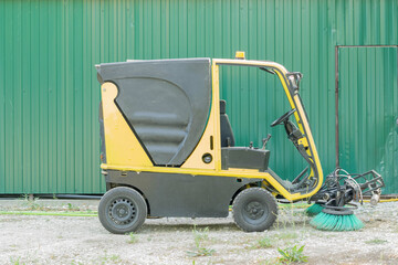 Yellow Industrial Street Sweeper Against Green Metal Garage Door