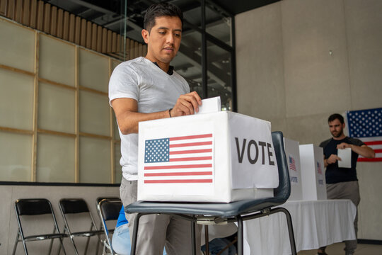 hispanic man placing his vote ballot in the polling box in the us elections of usa, cituzen voting in united states of america