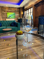 Single glass of white wine on a glass table surrounded with modern furniture