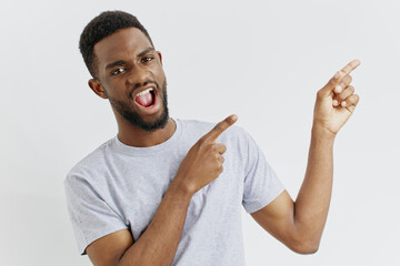 Young african american man enthusiastically pointing at a blank space, suggesting an idea or...
