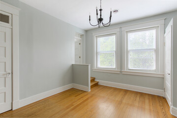 Beautiful Living Room With Wooden Floor, White Walls, Windows, And Chandelier
