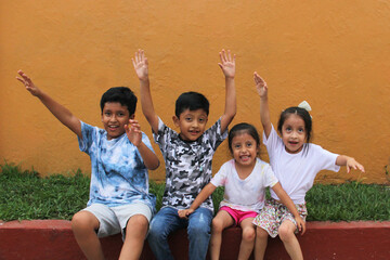 Two happy and excited dark-skinned Latino boys and 2 girls celebrate Children's Day by playing and laughing