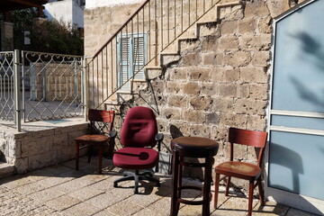 A lounge chair stands on the sidewalk on a street in a big city.