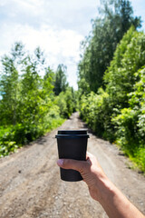 Fototapeta premium Hiker woman holding to go coffee cup in the forest.