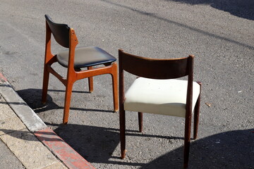 A lounge chair stands on the sidewalk on a street in a big city.