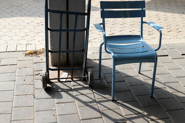 A lounge chair stands on the sidewalk on a street in a big city.