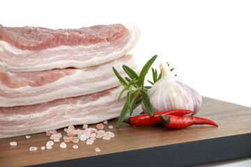 Raw pork belly slices with garlic and chili peppers on a wooden board