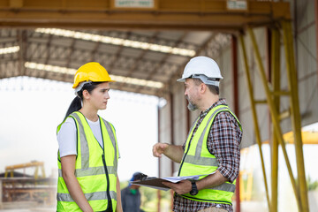 Engineer and foreman worker checking project at building site, Engineer and builders in hardhats discussing on construction site, Teamwork concepts