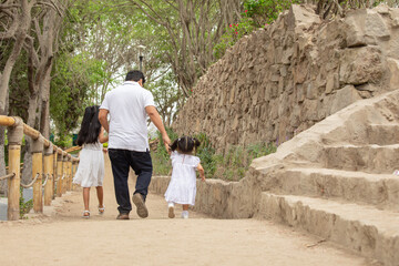 Family members holding hands while walking in a park during a sunny day in Lima Peru