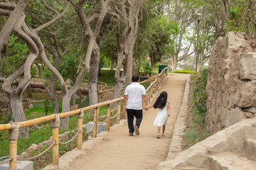 Fototapeta premium Family members holding hands while walking in a park during a sunny day in Lima Peru