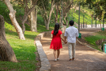 Fototapeta premium Family members holding hands while walking in a park during a sunny day in Lima Peru