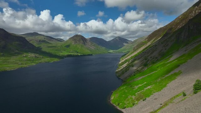 Steep mountainside dropping down to dark lake with mountains in distance. Lateral drone move over lake. Yewbarrow, Great Gable visible. Wastwater, Wasdale, Lake District, Cumbria, England, UK