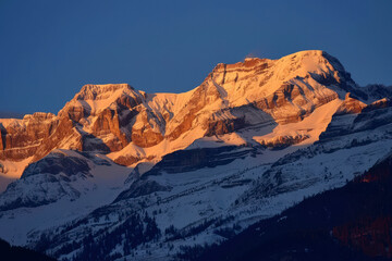 breathtaking mountain landscape at sunrise, with the first rays of light casting golden hues on snow-covered peaks